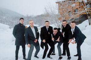A group of men posing for a picture in the snow. They are all dressed in suits and ties photo