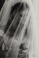 A woman is wearing a veil and holding a rose. The veil is white and covers her face, creating a sense of mystery and elegance. The rose adds a touch of romance and beauty to the scene photo