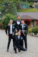 A group of men in suits are posing for a photo, with one man standing on the shoulders of the others. Scene is lighthearted and fun, as the men are enjoying themselves photo