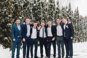 A group of men in suits are posing for a picture in the snow. Scene is festive and celebratory, as the men are dressed in formal attire and appear to be enjoying the winter weather photo