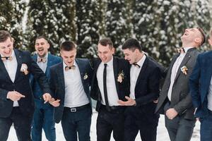 A group of men in suits are posing for a picture in the snow. They are all smiling and seem to be enjoying themselves photo