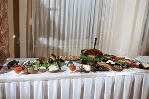 A table is covered with a variety of food, including a large salad. The table is set for a meal, and the food is arranged in bowls and on plates. The atmosphere is inviting and welcoming photo