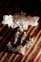A white lace train with a white band is on a red and gold striped background. The train is made of lace and is decorated with pearls photo