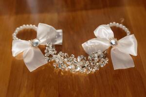 A pair of white bows are displayed on a wooden table. The bows are made of silver and are adorned with crystals. Concept of elegance and sophistication photo