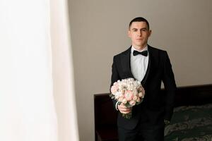 A man in a suit and tie holding a bouquet of flowers. Concept of elegance and sophistication, as the man is dressed in formal attire and the flowers add a touch of natural beauty to the scene photo