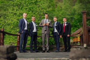 A group of five men are dressed in suits and ties, posing for a photo. Scene is formal and elegant, as the men are dressed in business attire photo