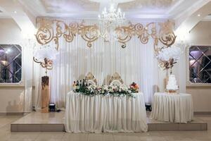 A large white table with a chandelier above it and a cake on it photo