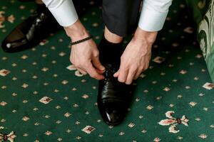 A man is putting on his shoes, and the image conveys a sense of formality photo