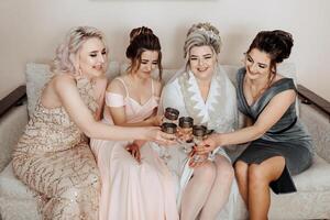 A group of women are sitting on a couch and drinking wine. They are all dressed up and smiling photo