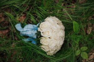 A bouquet of white roses is sitting in a field of grass. The flowers are arranged in a round shape and are surrounded by green grass. Concept of natural beauty and tranquility photo