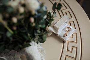 A bouquet of flowers sits on a table next to a white box containing two rings. Concept of love and commitment, as the rings symbolize a promise to be together forever photo