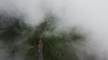 Descending flight through clouds over alpine green meadows. Fast flight down on fpv drone through dense thick clouds video