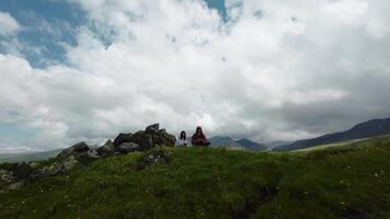 fpv drone pilot sits on the ground in the mountains with his girlfriend and films himself. virtual reality glasses on a person in nature video
