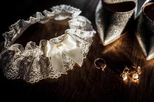 A white lace train with a bow is on a table next to a pair of silver shoes and a ring photo