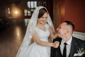 A bride and groom are posing for a picture in a church. The bride is wearing a white dress and a veil, while the groom is wearing a suit and tie. They are both smiling and seem happy to be together photo
