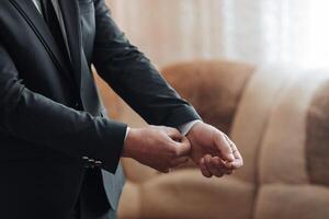 A man in a suit is getting ready for a formal event. He is adjusting his tie and shirt, and his hands are visible. Concept of preparation and formality photo