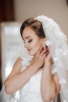 A woman is getting her ears pierced with a flowery veil in the background. The scene is intimate and romantic, with the bride-to-be looking into the camera photo