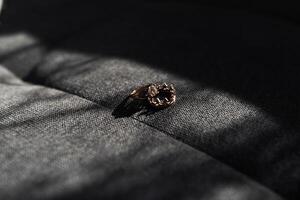 A ring is sitting on a gray surface. The ring is made of gold and has a design on it photo