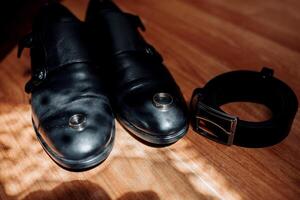 A pair of shoes with a ring on the toe and a belt on the floor photo