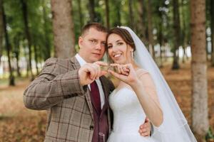 A bride and groom are posing for a picture with their hands together, holding a green ring. Concept of love and commitment, as the couple is celebrating their wedding day photo