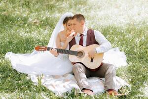 A man and woman are sitting on a blanket in a grassy field, with the man playing a guitar. Concept of love and intimacy photo