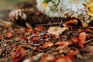 Two wedding rings are on a pile of leaves. The scene gives off a rustic and natural vibe, with the rings representing a couple's commitment to each other photo