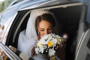A bride is in a car with a bouquet of flowers. She is holding the bouquet and talking on her cell phone photo