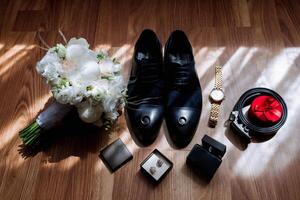 A man's outfit is displayed on a wooden table, including a watch, a belt, and a pair of shoes photo