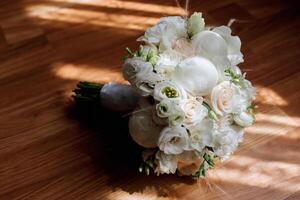A bouquet of white flowers sits on a wooden table. The flowers are arranged in a way that they are all facing the same direction, creating a sense of harmony and balance photo