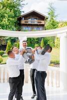 A group of men are playing with a child, one of whom is holding the child. Scene is lighthearted and playful photo