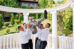 A group of men are playing with each other, one of them is lifting another man. Scene is lighthearted and fun photo