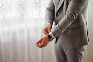 A man in a suit is adjusting his watch. Concept of formality and attention to detail photo
