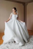 A bride in a white dress is posing for a picture. She is wearing a veil and has her arms outstretched. The image has a happy and celebratory mood, as it captures a special moment in the bride's life photo
