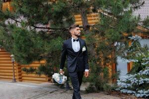 A man in a suit and tie is walking down a path with a bouquet of flowers in his hand photo