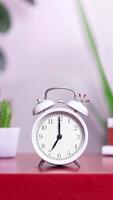 Alarm clock is ringing at 7 am. Looped stopmotion animation footage white Old fashioned alarm clock ringing on the hour, clock staggers from side to side and rings drawn motion elements vertical video