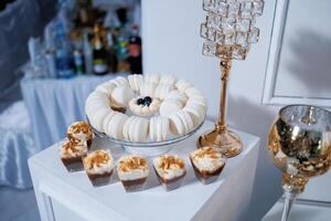 A table with a variety of desserts, including macaroons and cakes, and a tall glass vase with a candle in it photo