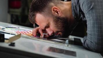 Worker in a printing and press center uses a magnifying glass and check the print quality video