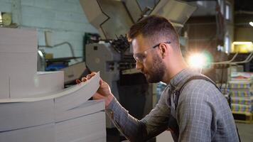 Print worker ready to place blank sheets of paper into offset machine for printing. video