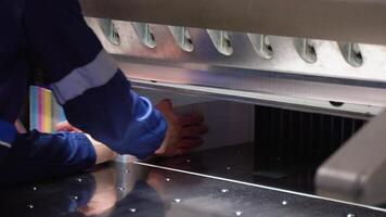 Worker cutting paper using paper cutting machine in a printing factory. Printing cutting machine, final cut video