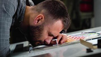 Worker in a printing press factory uses a magnifying glass and check the print quality video