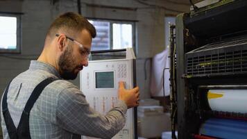 Technician operator checking input and output status on touchscreen front display monitor station in digital printshop office video