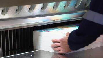 Worker cutting paper using paper cutting machine in a printing factory video