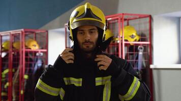 Firefighter putting on protective helmet and preparing for action while standing in fire station video