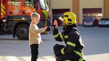 Firefighter in uniform is with a little boy at fire station video