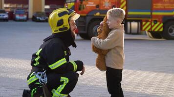 Firefighter in uniform with a little boy near a fire engine at station video