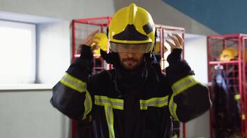 Firefighter putting on protective helmet and preparing for action while standing in fire station video