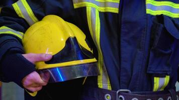 Firefighter with helmet in her hands standing at station, close up video