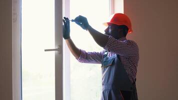 African american foreman installs a window frame in the room video