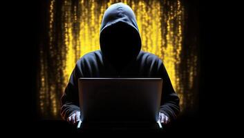 A hooded figure cloaked in shadow, illuminated by the eerie glow of a computer screen, embodying the dangers of the digital world. photo