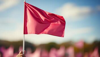 A single red flag waves prominently against a blurred background of pink flags and a blue sky. for signaling, awareness, and standing out. photo